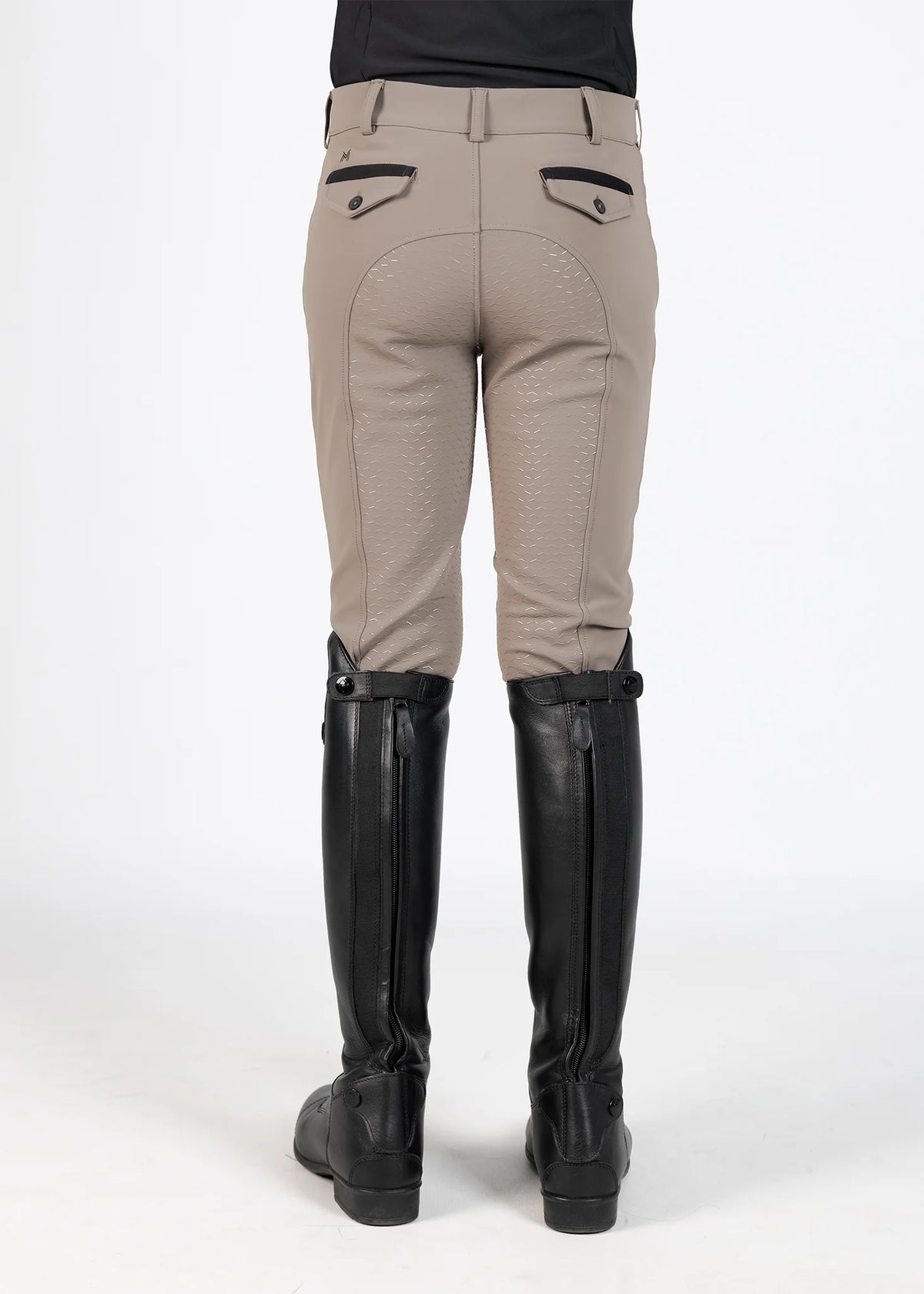 Beige riding pants with black knee patches and tall black boots on a white background